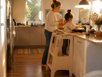 Parent cooking while a child helps from the Learning Tower nearby